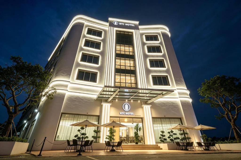 a building with chairs and umbrellas in front of it at BTC Hotel 比特币酒店 in Malacca