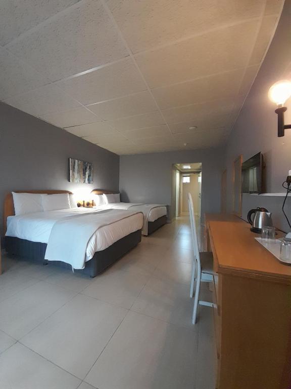 a hotel room with a bed and a desk and a kitchen at Matsapha Hotel in Mahlanya