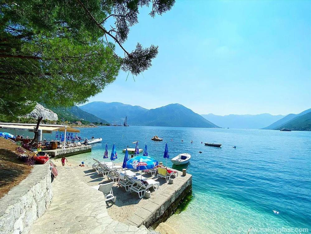 a beach with chairs and umbrellas in the water at Eco Bay Montenegro in Donji Morinj
