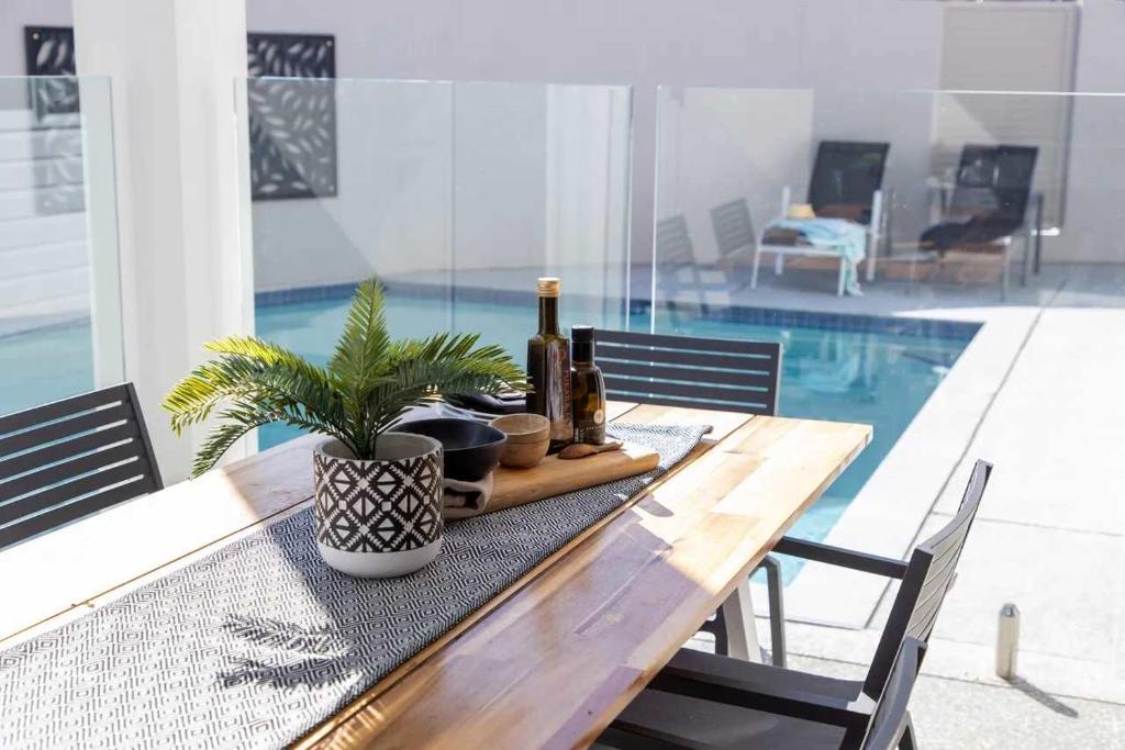 a wooden table with a potted plant on it next to a pool at Waves Beach House in Marcoola