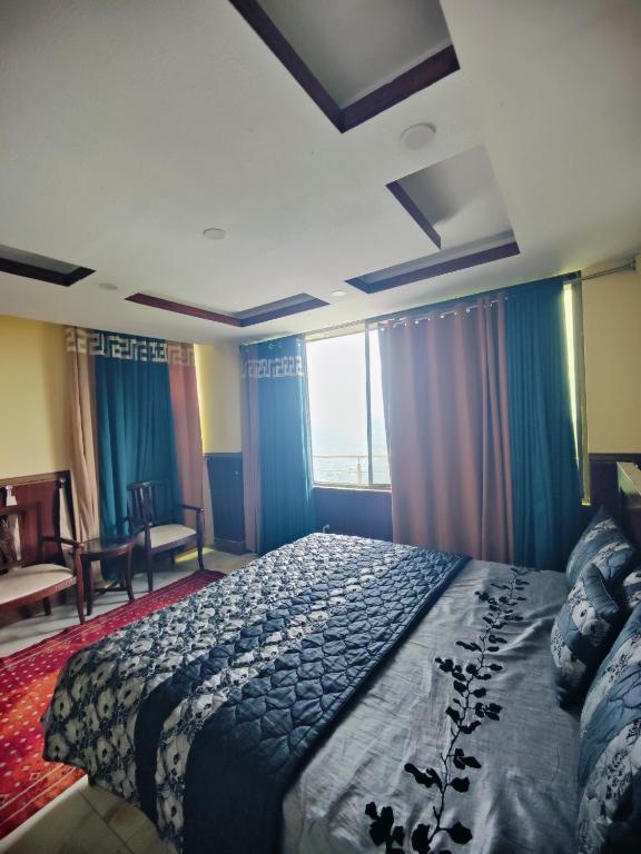 a bedroom with a bed and a large window at Stylish Apartment in Khaira Gali