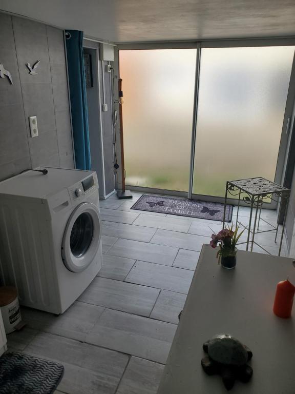 a laundry room with a washing machine and a table at Les flots d'Émilie et Vincent in Barneville-Carteret