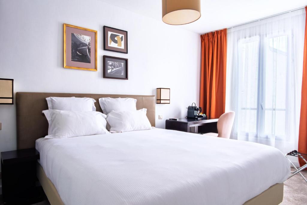 a bedroom with a large white bed and a window at Hotel Frochot Montmartre in Paris