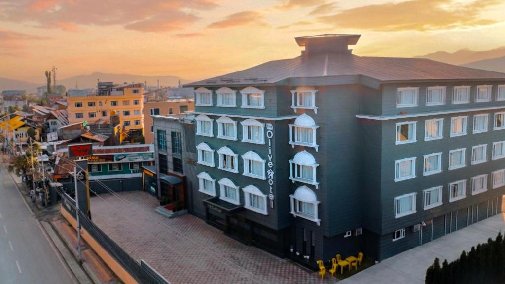 a large building with white windows on a city street at The Olive Hotel Srinagar in Srinagar