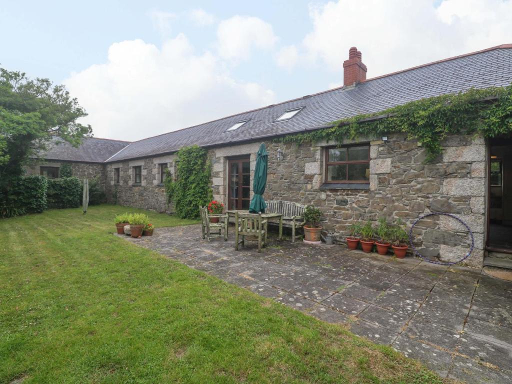 a stone house with a patio and a yard at Swallow Cottage in Helston