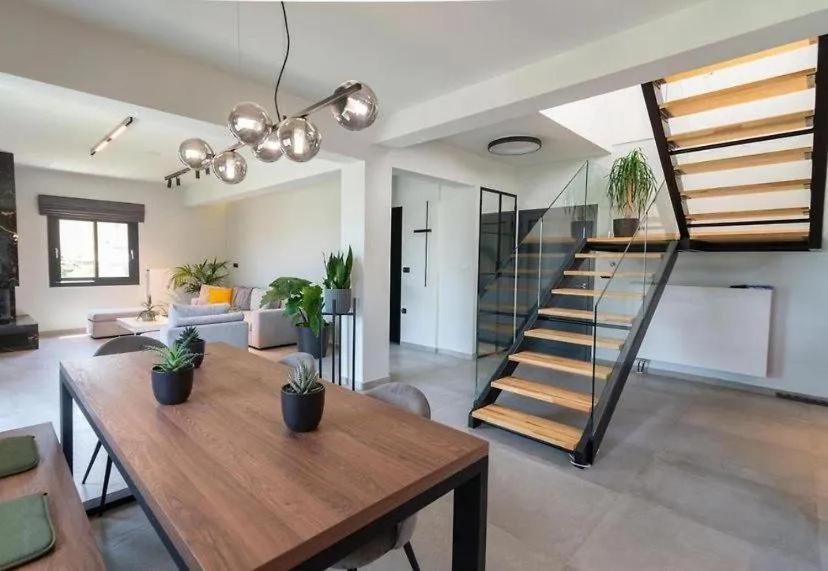 a living room with a wooden table and a staircase at Greenery Luxury Apartment in Potamós