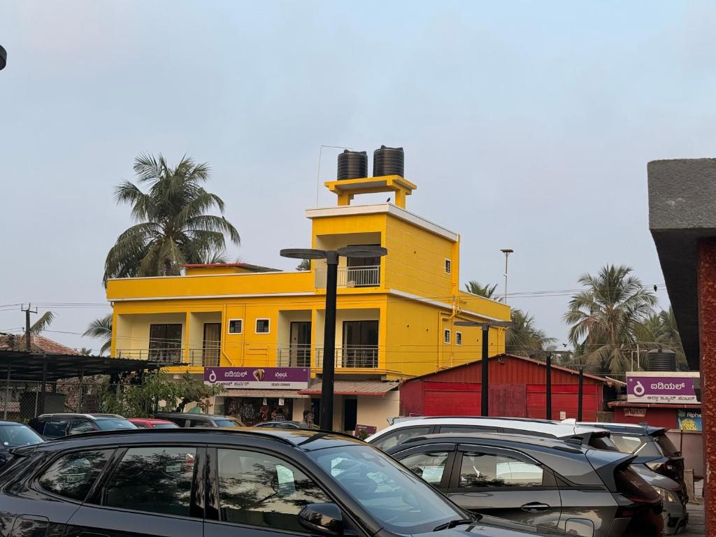a yellow building with cars parked in front of it at Golden rays beach stay in Mangalore
