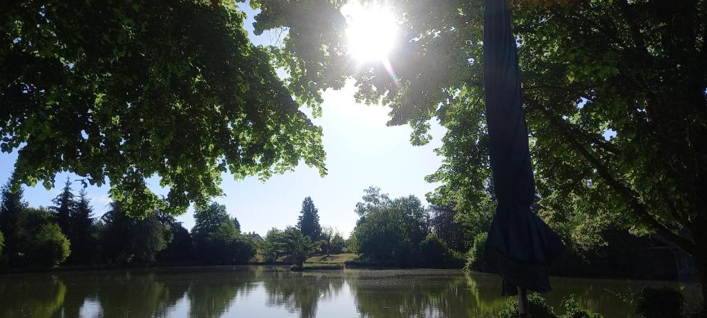 a view of a lake with the sun shining through trees at Summers Breeze in Nantheuil