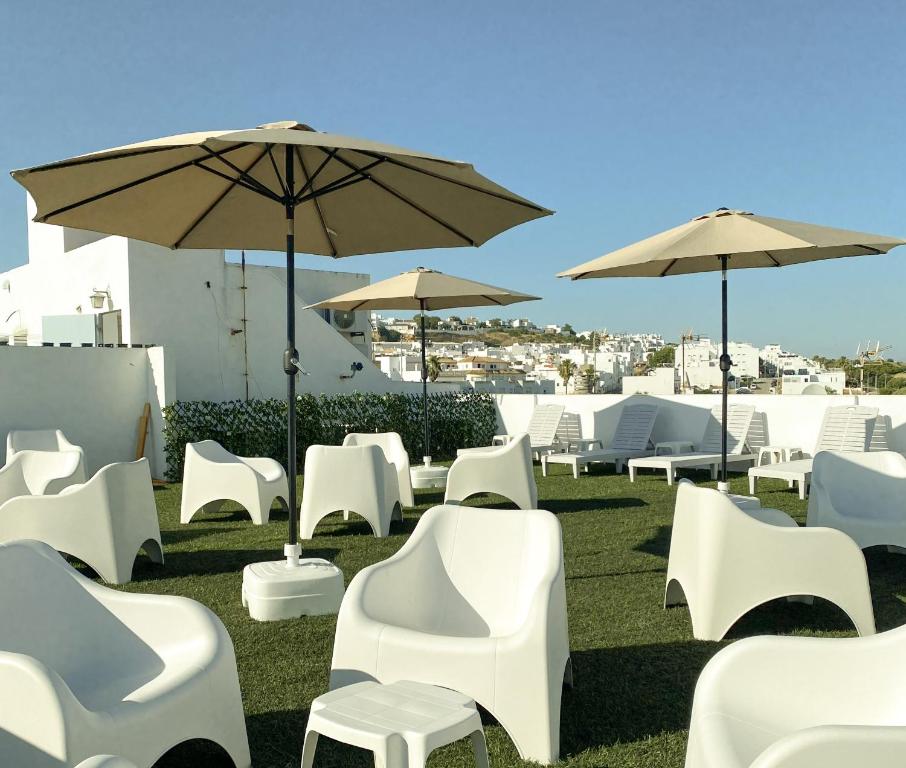 a group of white chairs and umbrellas on the grass at 1 linea de playa - Apartamentos - Beach & River - Conil in Conil de la Frontera