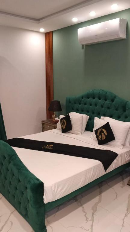 a large bed with a green headboard in a room at Palmtree Hotel in Lahore