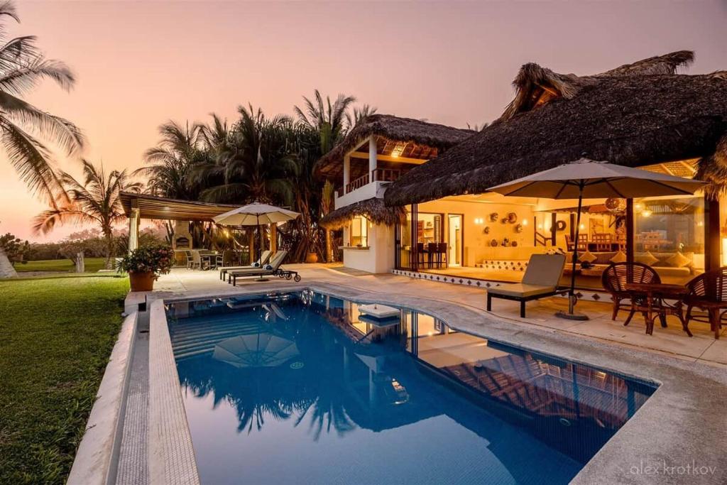 a house with a swimming pool in front of a house at Casa Fuente Ocean Villa in Santa María Colotepec