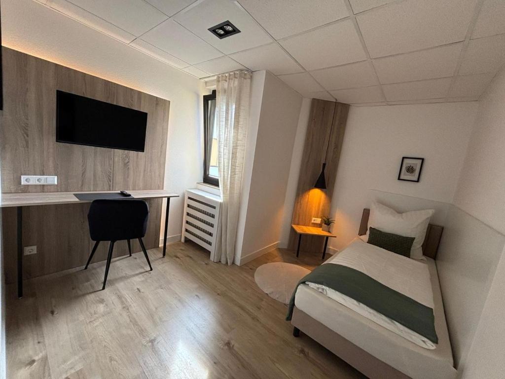ein Schlafzimmer mit Bett, Schreibtisch und Fernseher in der Unterkunft Vintage HOTEL S-Weilimdorf in Stuttgart-Weilimdorf