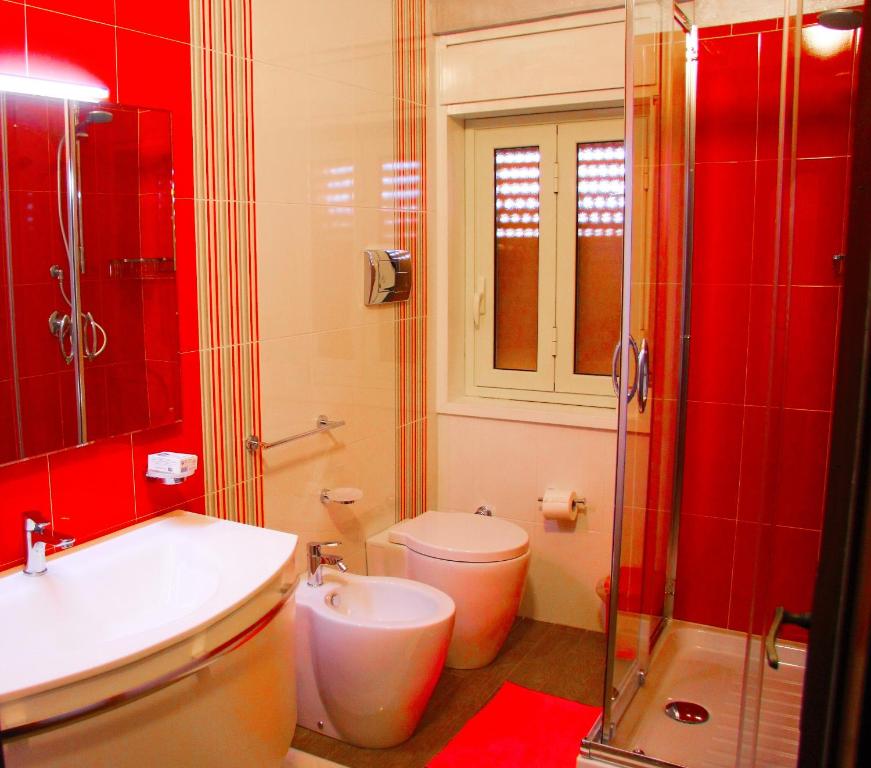 La salle de bains rouge est pourvue d'une douche et de toilettes. dans l'établissement Happy Holiday Villa, à Syracuse