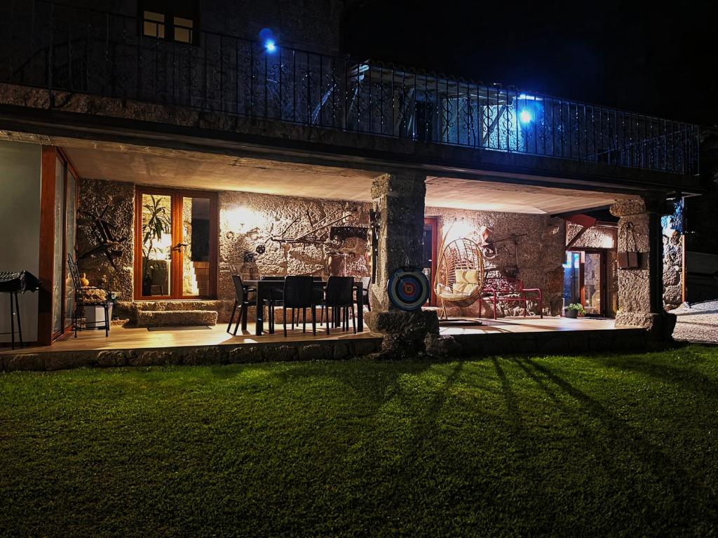 a house at night with a table and chairs at Quinta da Casa dos Santos - Inside Gerês in Geres