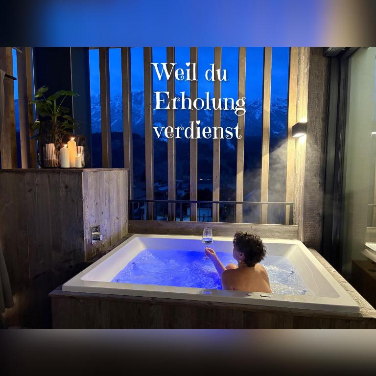 a man in a bath tub with a glass of wine at Aloha Suite - Schladming Dachstein in Haus im Ennstal