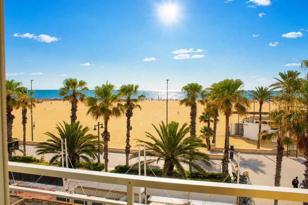 a view of the beach and palm trees from a balcony at Malvarrosa Beach Rooms in Valencia