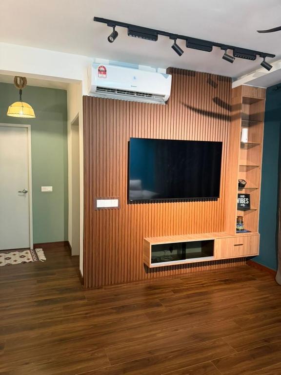 a living room with a flat screen tv on a wooden wall at The Amour Suite in Teluk Panglima Garang