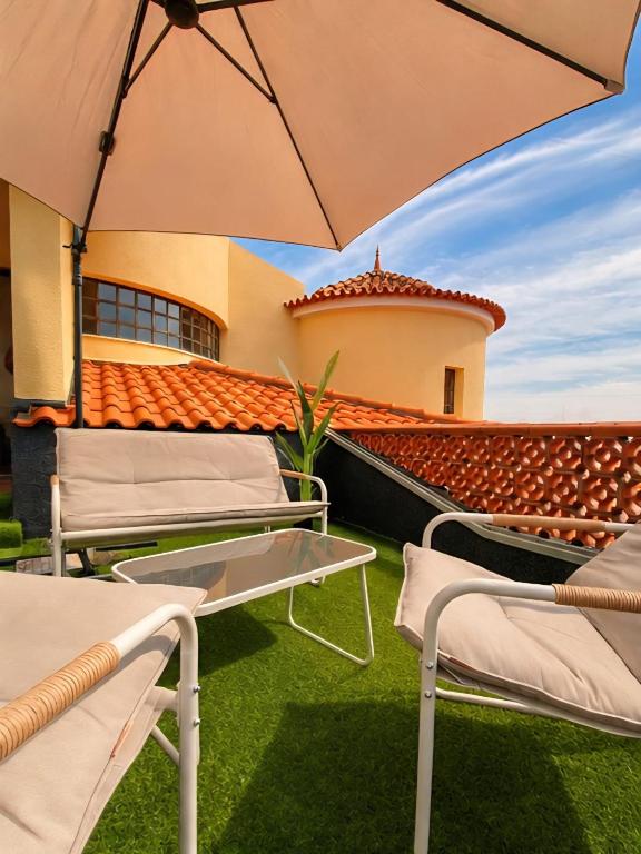 a patio with chairs and an umbrella in front of a building at Villa Salgado in Gafanha da Nazaré