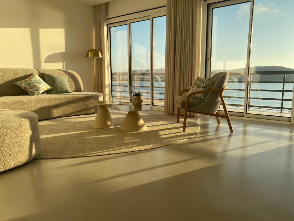 a living room with a couch and a chair and a large window at Beachfront 3bdr apt on Marginal Boulevard in São Martinho do Porto