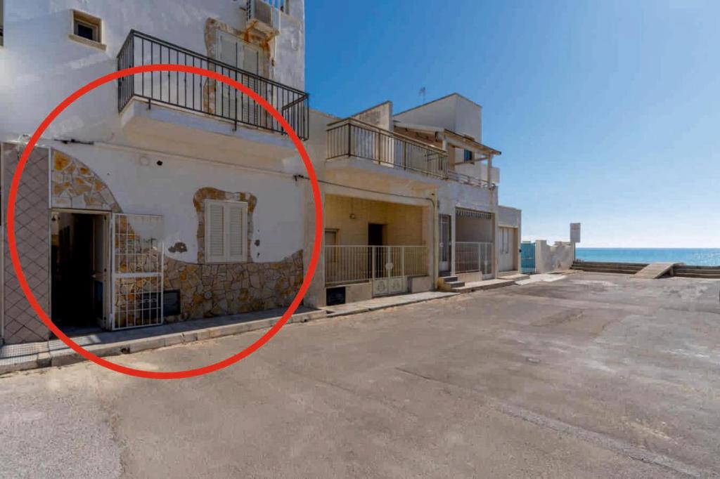 a large white building with a red circle on it at A due passi dal Mare in Torre Lapillo