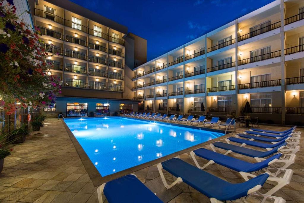 ein großer Pool mit Liegestühlen vor einem Hotel in der Unterkunft Coast Capri Hotel in Kelowna