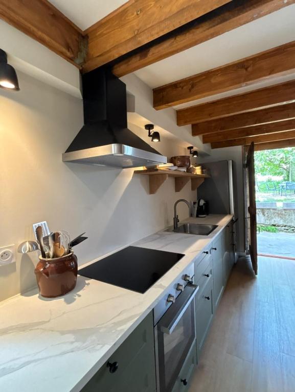 a kitchen with a sink and a stove at Gîte La Vielle Forge in Virazeil