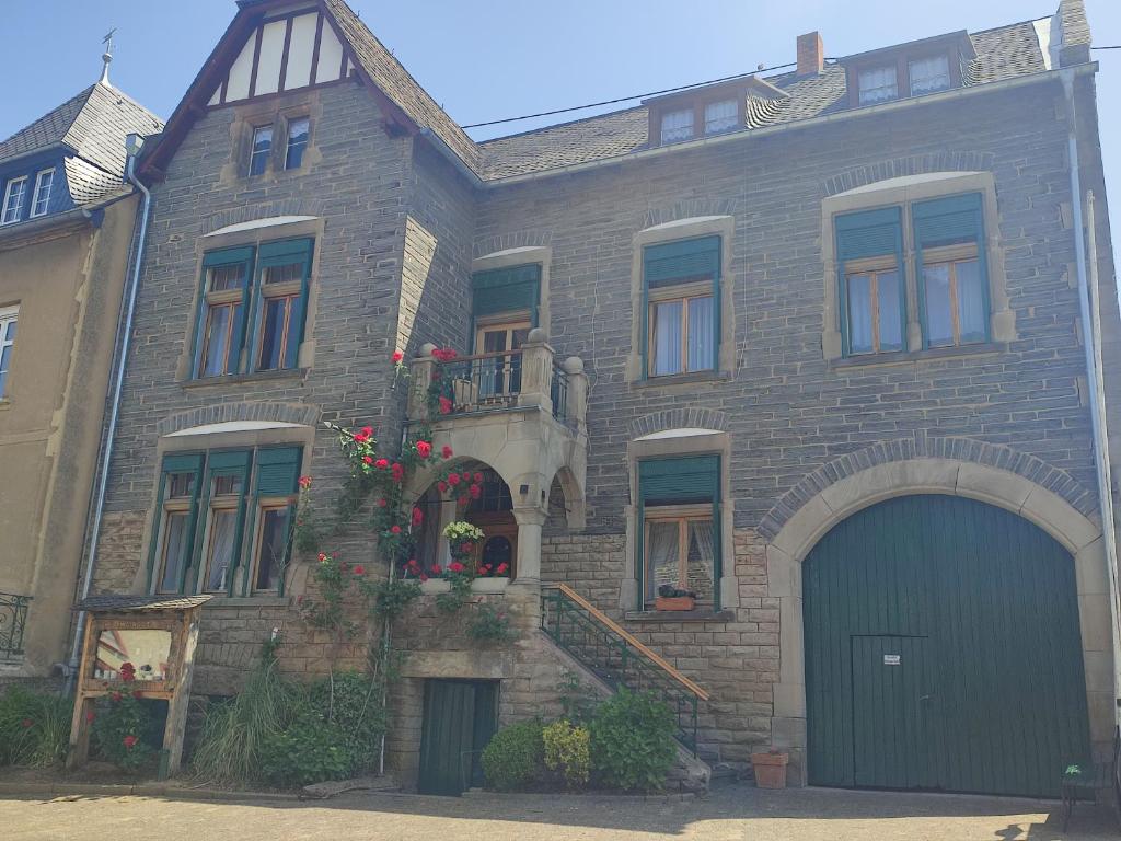 a large brick house with a green garage at Bed & Breakfast - Haus Hubertus in Brauneberg