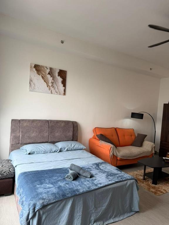 a bedroom with a bed and an orange chair at Cozy Stay Studio in Shah Alam