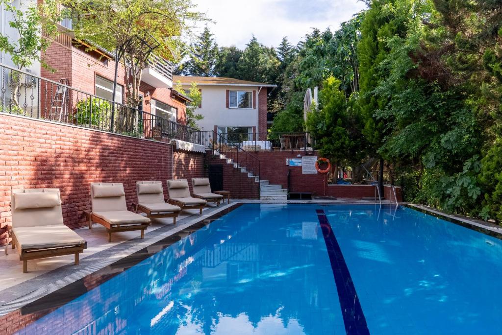a swimming pool with lounge chairs next to a building at Büyükada Apart Hotel in Adalar