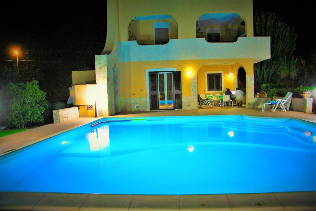 a swimming pool in front of a house at night at Happy Holiday Villa in Siracusa