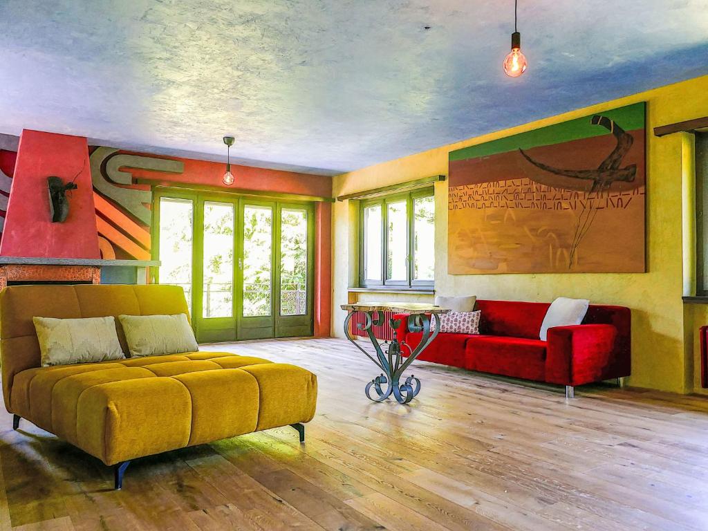 a living room with a yellow couch and red chairs at Apartment Casa Malva by Interhome in Malvaglia