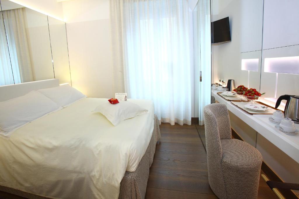 a hotel room with a bed and a desk with a chair at Hotel Berna in Milan