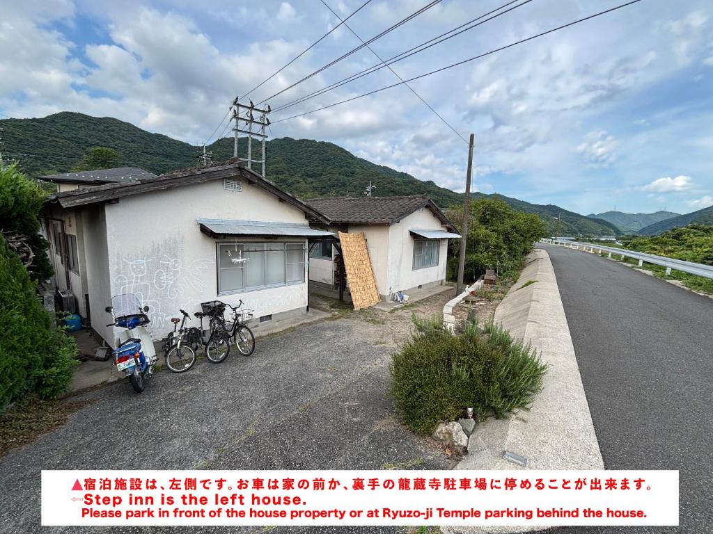 a house with two bikes parked next to a road at 古民家宿Step inn Hagi なかつえ in Hagi