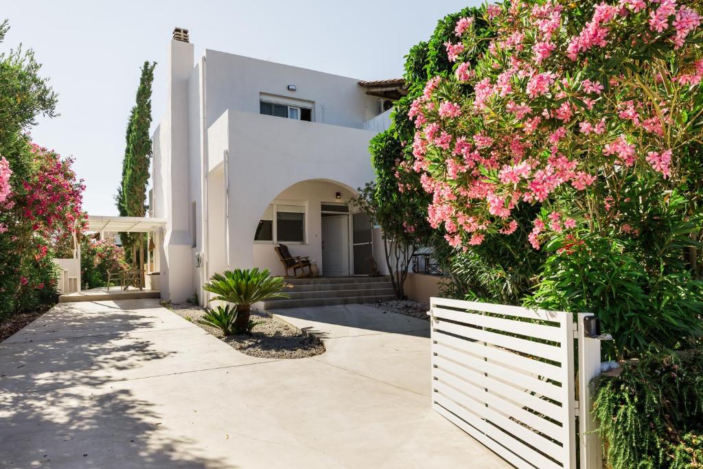 a white house with pink flowers and a white fence at PhώS Casa Lachania in Lachania