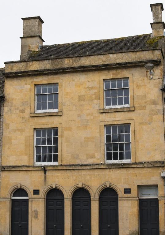an old brick building with black doors and windows at Cotswold Townhouse - Adults Only in Stow on the Wold