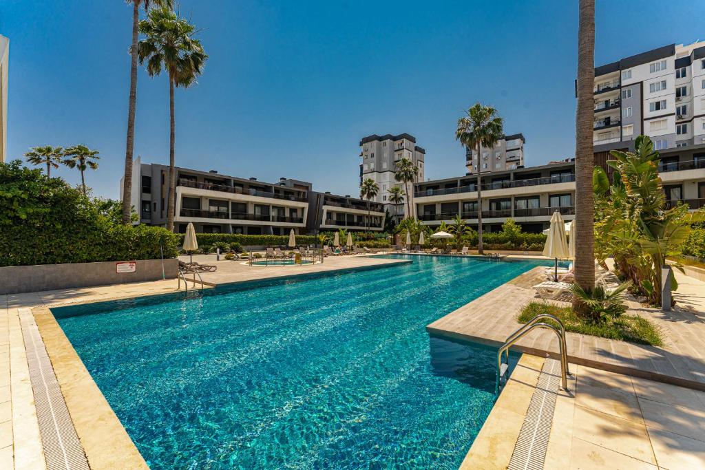 a large swimming pool with palm trees and buildings at Bliss Residance in Altınkum