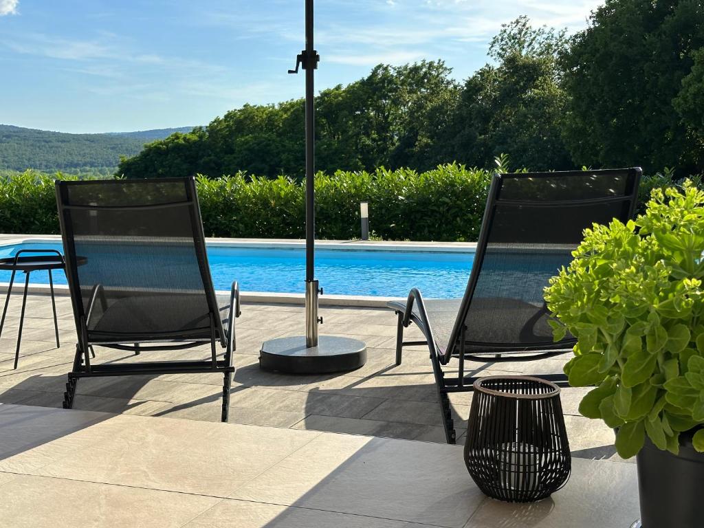 two chairs and a table next to a pool at Villa Olealis in Zatka Čepić