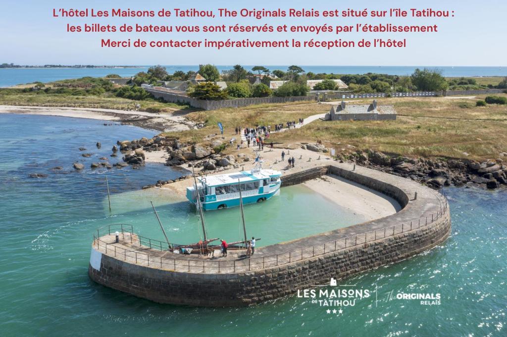 a boat in the water next to a pier at Les Maisons de Tatihou, The Originals Relais in Saint-Vaast-la-Hougue