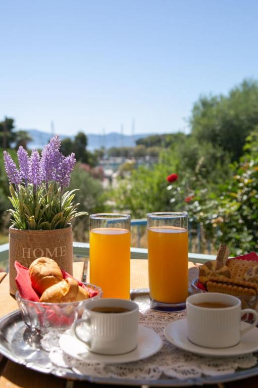 ein Tisch mit zwei Gläsern Orangensaft und einem Teller Essen in der Unterkunft Aerides Studios in Methana