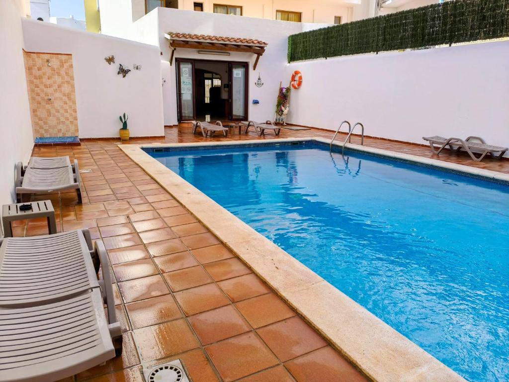 a large swimming pool with chairs and a swimming pool at Hostal Horizonte in San Antonio