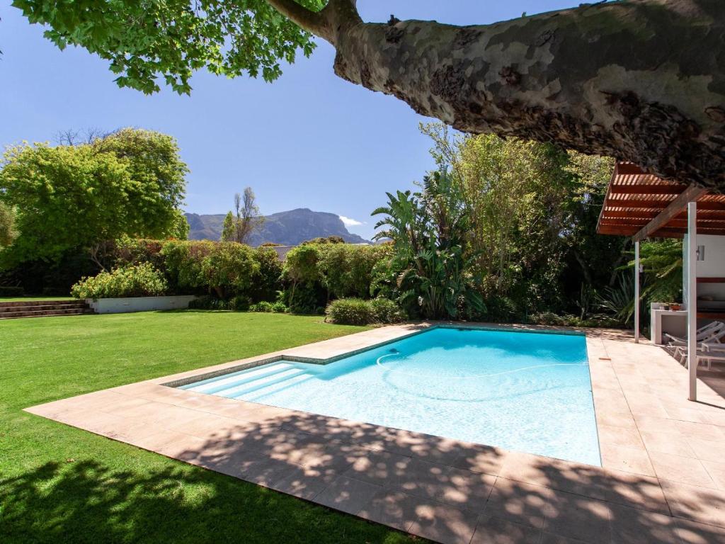 a swimming pool in a yard with a tree at The Barn Style Cottage in Cape Town