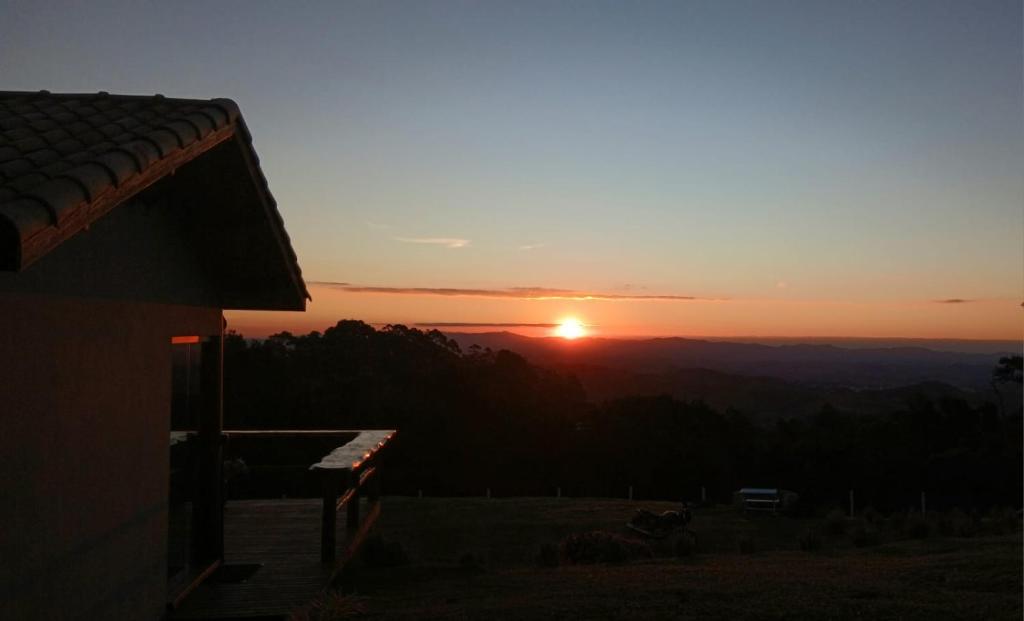 a sunset in the mountains with a bench in the foreground at Chalé Pôr do Sol in Cunha