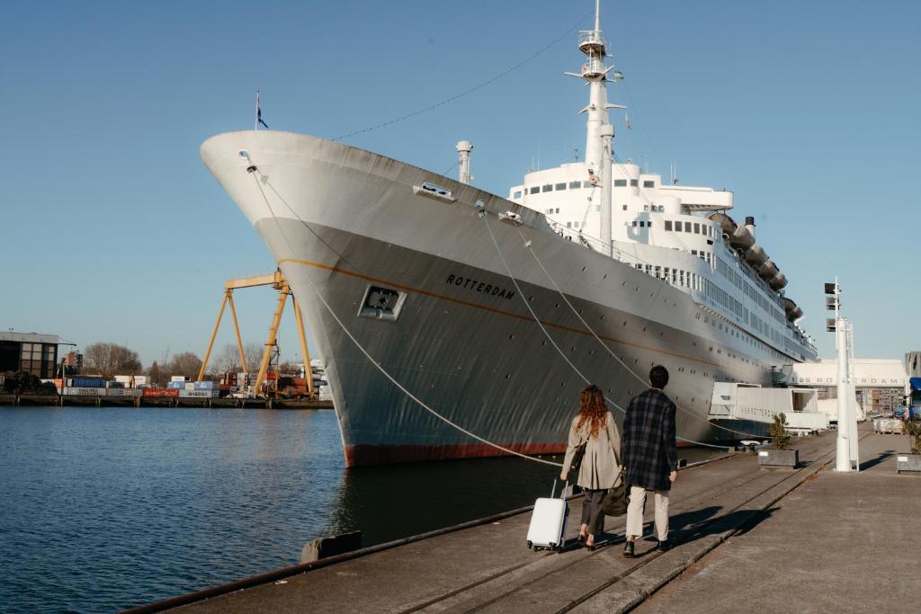 a man and woman standing next to a cruise ship at ss Rotterdam by WestCord in Rotterdam