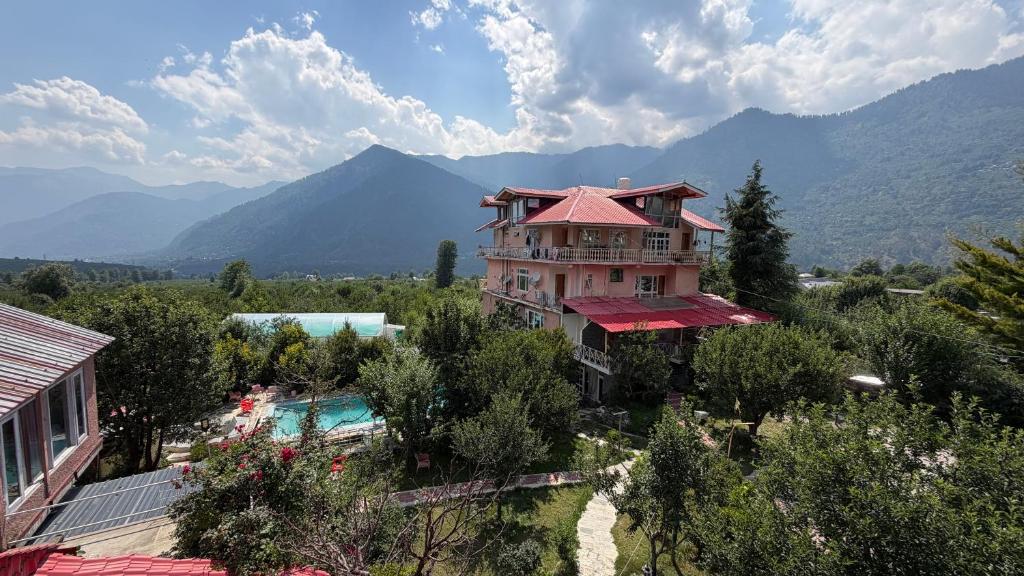 a building with a pool and mountains in the background at Countryside Himalayan Resort in Manāli