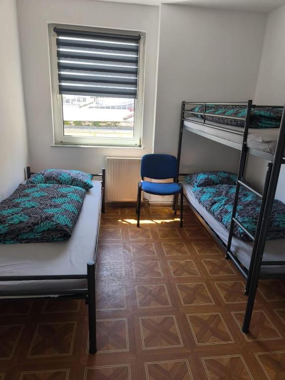 a room with two bunk beds and a blue chair at Pokoje gościnne in Lubniewice