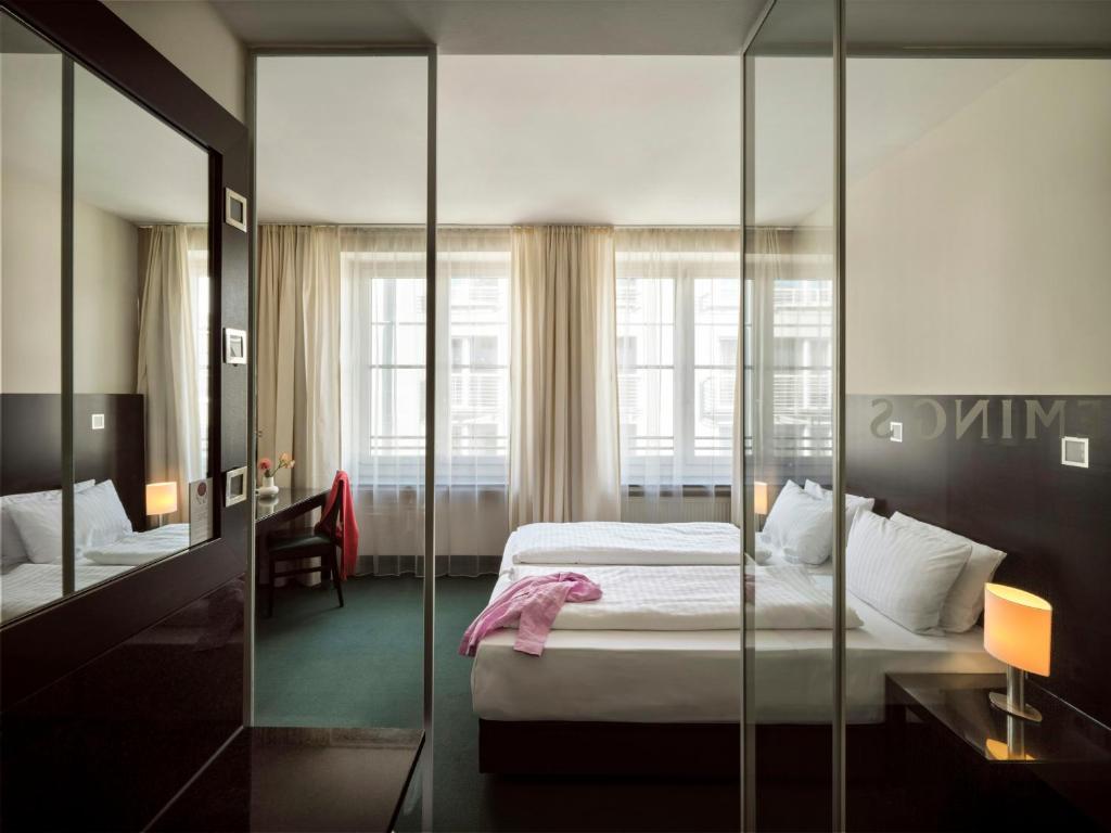 a hotel room with a bed and a mirror at Flemings Hotel München-City in Munich