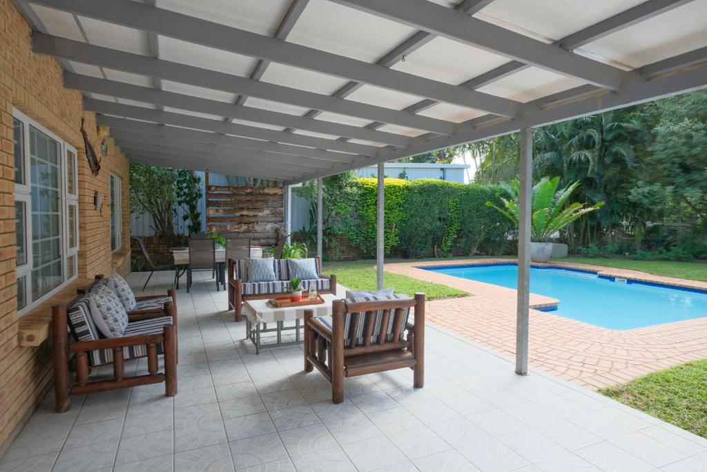 a pergola over a patio with chairs and a pool at Kuda Breeze in St Lucia