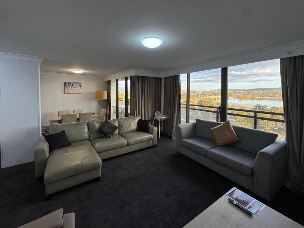 a living room with a couch and chairs and a large window at Lakefront Panorama – Classic in Canberra