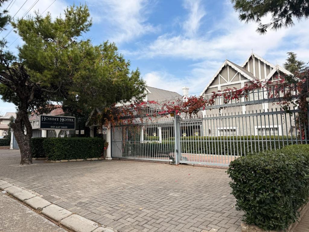 a white building with a fence with flowers on it at Hobbit Boutique Hotel in Bloemfontein