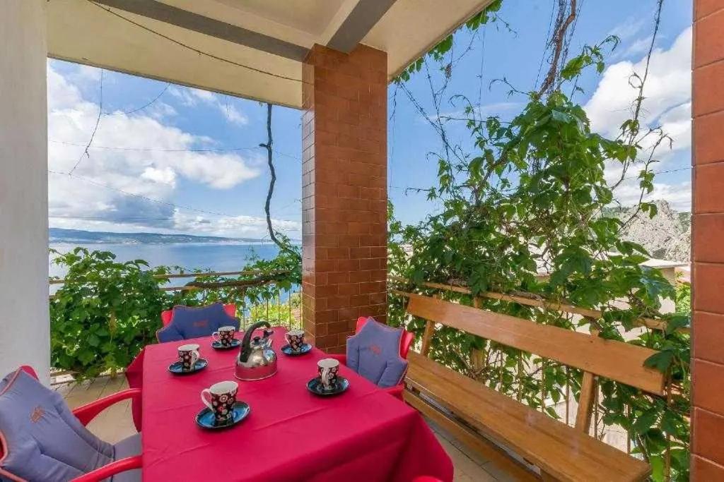 a table with a red table cloth on a balcony with a view at Apartmani Jasna in Omiš